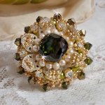 Bague L’Oiseau des Iles Vert Argent avec un cabochon Vert sur une estampe Argentée ornée de cristaux : toupies et chatons. Les perles rondes nacrées Ivoire et Olivine complète cette bague réglable. 